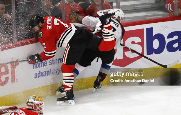 Brent Seabrook of the Chicago Blackhawks hits the boards battling with J.T. Compher of the Colorado Avalanche at the United Center on March 20, 2018...