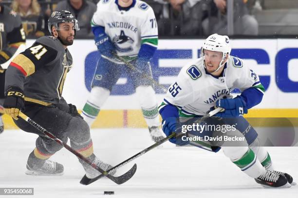 Alex Biega of the Vancouver Canucks skates with the puck while Pierre-Edouard Bellemare of the Vegas Golden Knights defends during the game at...