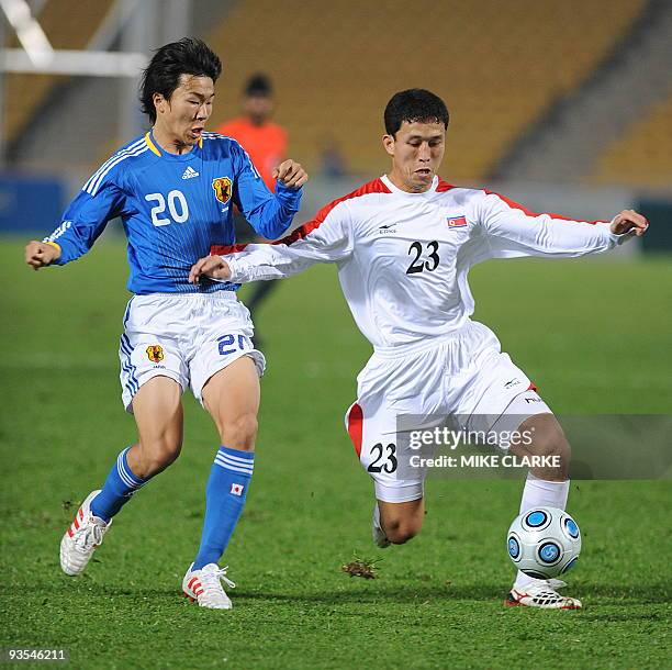 Kensuke Nagai of Japan tackles North Korean Pak Nam Chol in their preliminary round football match for the 2009 East Asian Games in Hong Kong on...