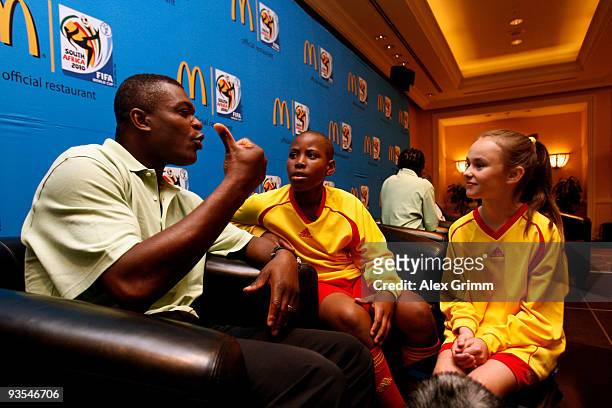Former French football player Marcel Desailly chats with McDonald's Player Escorts Bandile Skweyiya and Madri Du Plessis during a press conference of...