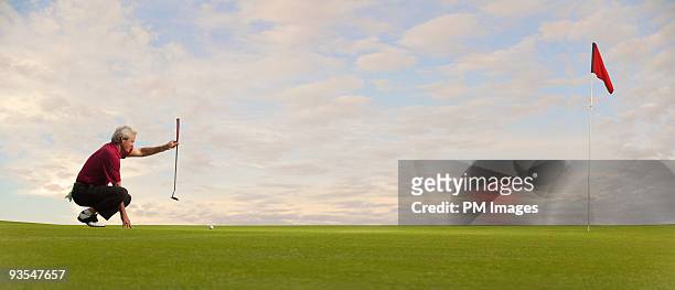 mature golfer lining up a putt - golf putter stock pictures, royalty-free photos & images