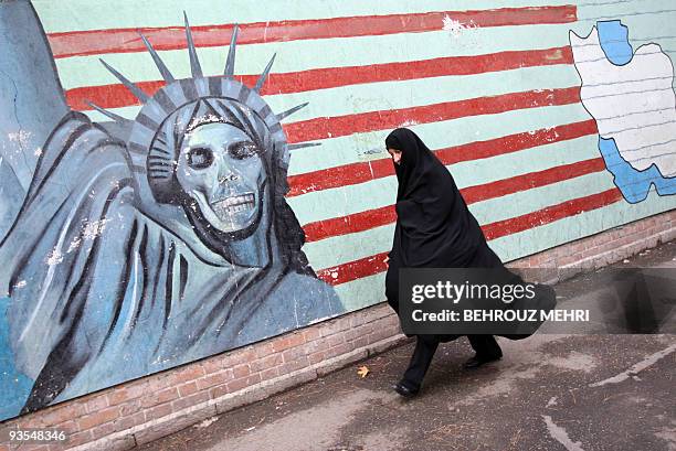 An Iranian woman walks past an anti-US mural painted on the wall of the former US embassy in Tehran on November 4, 2009 to mark the storming of the...