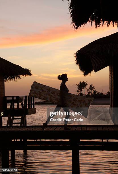 silhouette of woman carrying lilo in maldives - anantara stock pictures, royalty-free photos & images