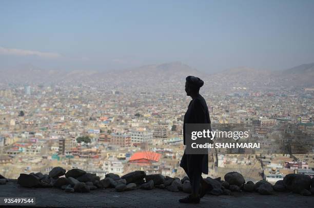 An Afghan man walks during the first day of the Nowruz , or Persian New Year, in a hilltop overlooking of Kabul on March 21, 2018. / AFP PHOTO / SHAH...