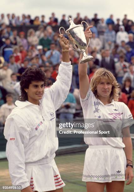 Gabriela Sabatini of Argentina and Steffi Graf of West Germany lift the trophy after defeating Larisa Savchenko and Natasha Zvereva both of the...