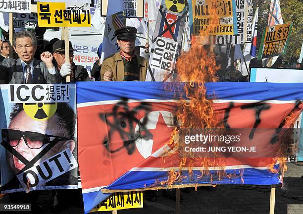 South Korean conservative activists burn a North Korean flag and a portrait of its leader Kim Jong-Il during a rally in Seoul on November 11, 2009...