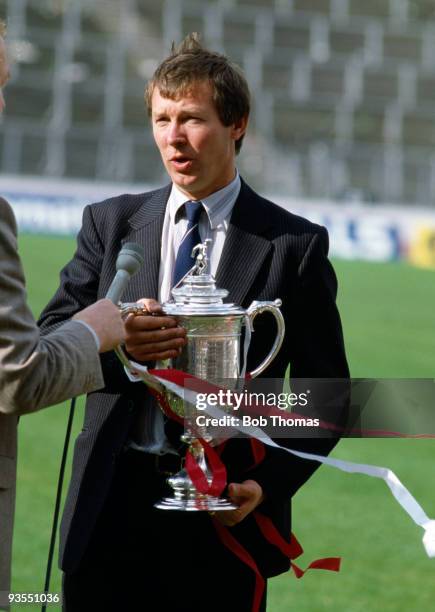 Aberdeen manager Alex Ferguson holds the Cup while being interviewed for television after his team's victory over Glasgow Rangers in the Scottish FA...