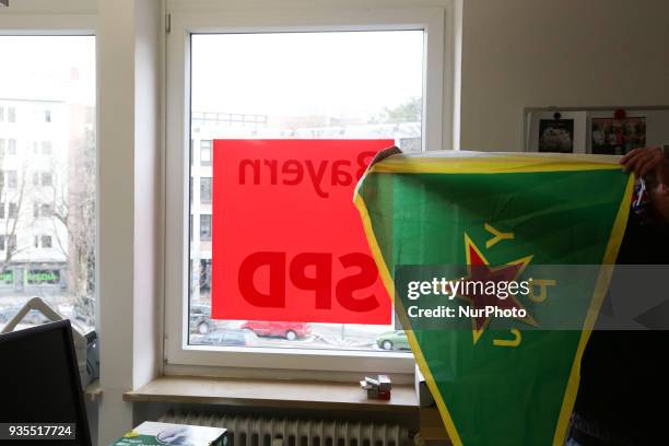 Activist holds flag of the women's defense unit next to the logo of the SPD, in Munich, Germany, on March 20, 2018. About 20 pro-kurdish activists...