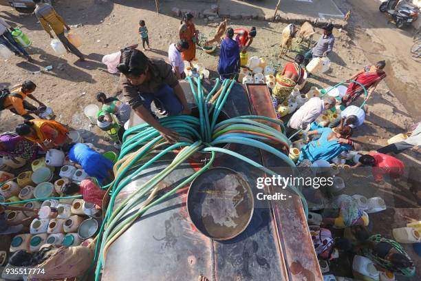 Indian slum dwellers collect potable water from a municipal water tanker in Durga Nagar area of Bhopal on March 21, 2018. - Slum dwellers depend on...