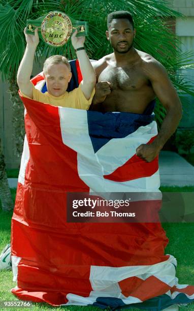 World Heavyweight Boxing Champion Lennox Lewis of Great Britain with his manager Frank Maloney holding the WBC Title belt and wrapped in a Union Jack...