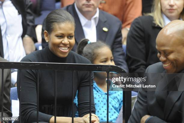 Michelle Obama and Craig Robinson, head coach of the Oregon State Beavers, smile at each other during a college basketball game against the George...