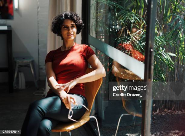 portret van midden-oosten jonge vrouw thuis in de buurt van venster - assertive stockfoto's en -beelden