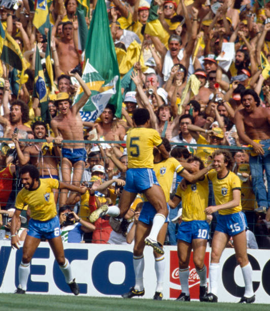 Toninho Cerezo of Brazil jumps onto goal scorer Socrates as the team celebrate in front of their fans during the Italy v Brazil World Cup match...
