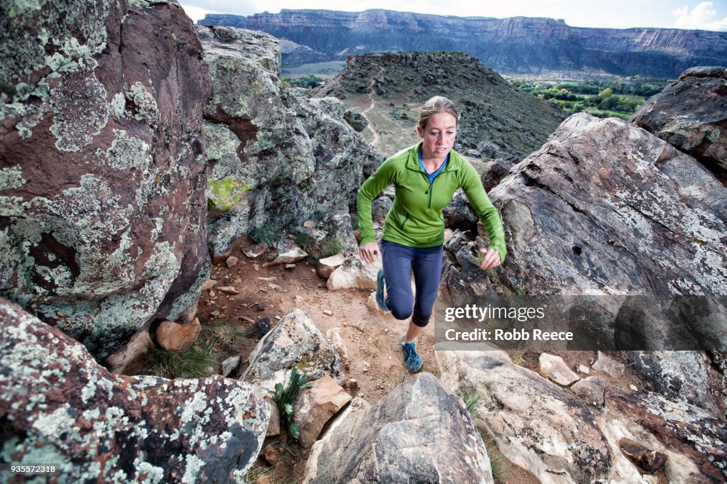 An adult woman trail running on a remote dirt trail
