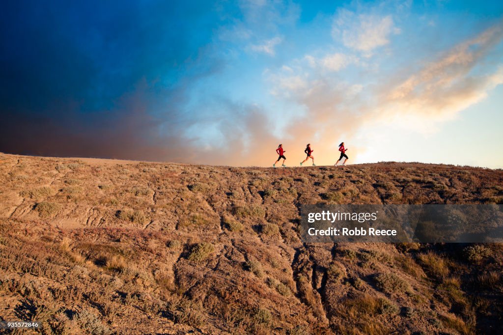 Three women trail running in the desert at sunrise