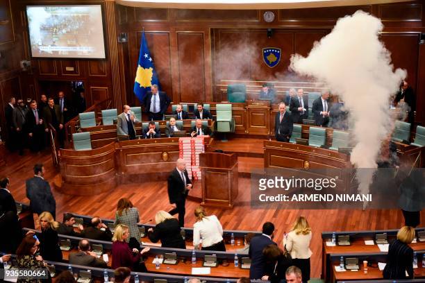 Kosovo's lawmakers react ans evacuate after opposition members released a teargas canister inside the country's parliament in Pristina on March 21,...