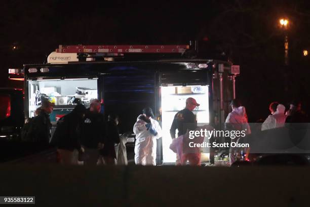 Law enforcement officials put on protective gear as they investigate at the location where the suspected package bomber was killed in suburban Austin...