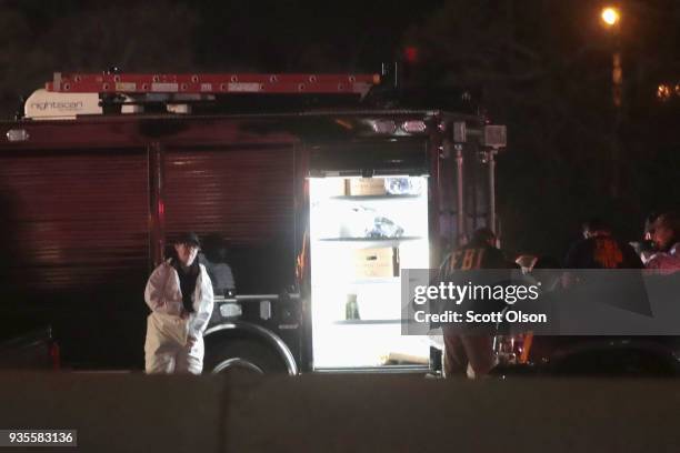 Law enforcement officials put on protective gear as they investigate at the location where the suspected package bomber was killed in suburban Austin...