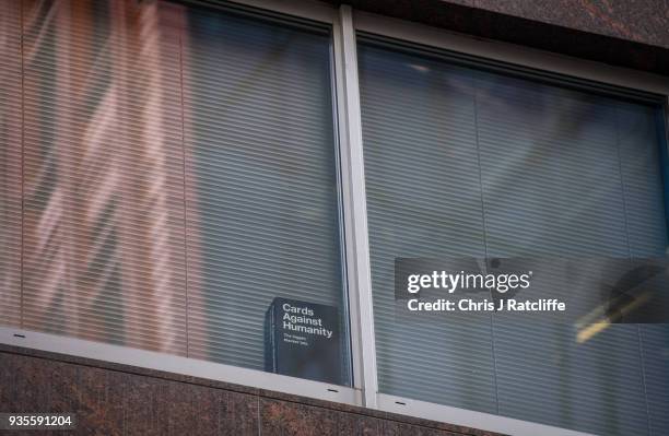 Copy of the game 'Cards Against Humanity' is seen in a the window of the floor occupied by company Cambridge Analytica on March 21, 2018 in London,...