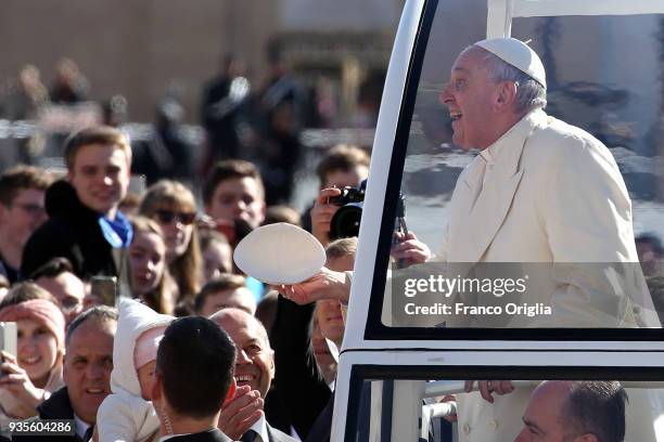 Pope Francis exchanges his biretta cup with a faithful as he arrives in St. Peter's Square for the weekly audience in St. Peter's Square on March 21,...