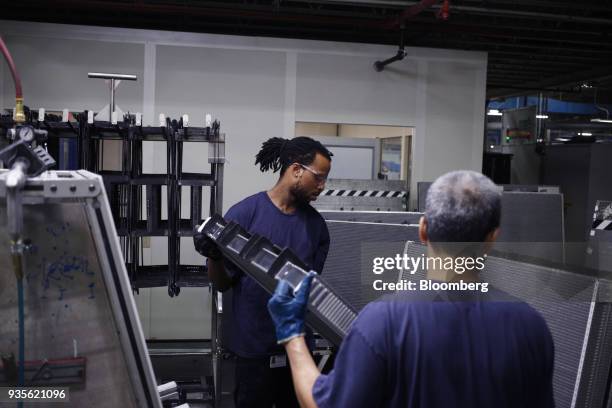 Workers carry a truck engine cooling module component at the MAHLE Behr Charleston Inc. Auto part facility in Charleston, South Carolina, U.S., on...