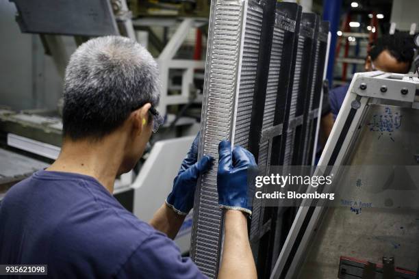 Workers carry a truck engine cooling module component at the MAHLE Behr Charleston Inc. Auto part facility in Charleston, South Carolina, U.S., on...