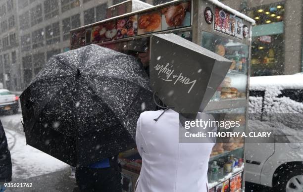 Lord and Taylor employee covers her head in the snow on 5th Avenue in New York on March 21 as the fourth nor'easter in a month hits the tri-state...