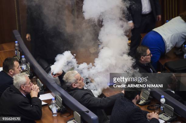 Kosovo opposition lawmaker throws a tear gas canister during a parliament session in Pristina on March 21, 2018 before a vote to ratify or not a...