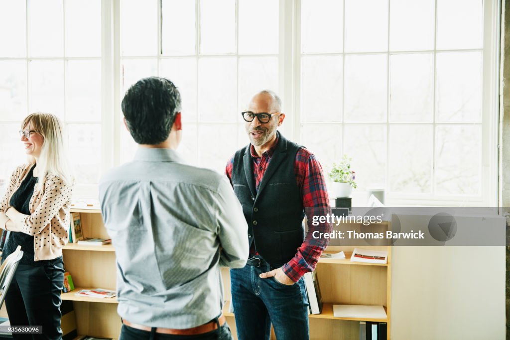 Smiling businessman having informal project meeting with coworker in design office