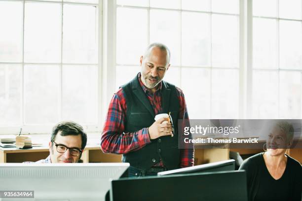 business colleagues reviewing project on monitor at workstation in design office - old wise business man white stock pictures, royalty-free photos & images