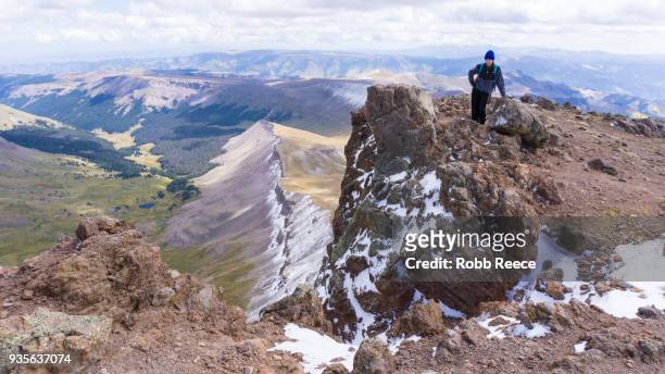a young man standing alone on a remote mountain peak - robb reece stockfoto's en -beelden