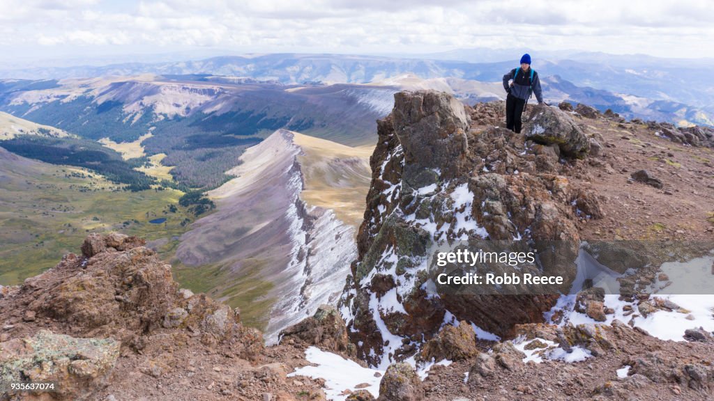 A young man standing alone on a remote mountain peak