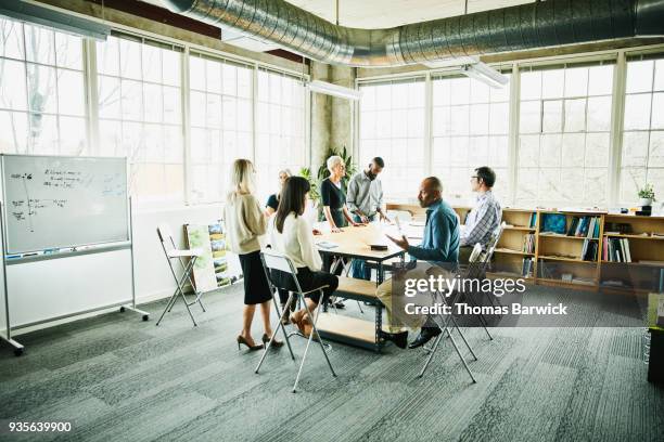 architects and engineers in project planning meeting at conference table in design studio - studio workplace stock-fotos und bilder