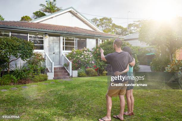 happy mixed-race couple standing in front of house - sydney houses stock pictures, royalty-free photos & images