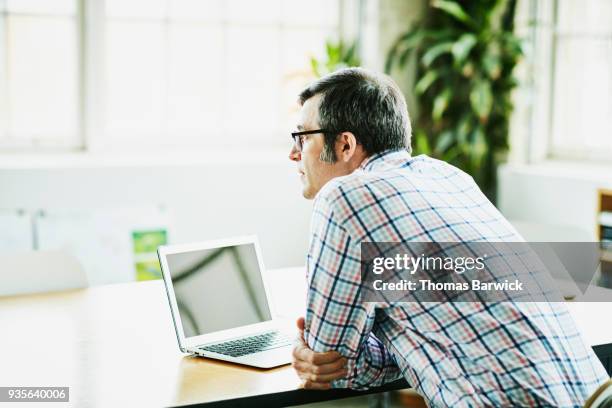 businessman sitting at office conference table working on laptop - bookstand stock pictures, royalty-free photos & images