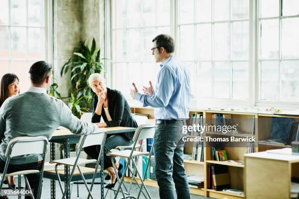 businessman leading team meeting in design studio conference room - responsabilities experience advice photos et images de collection