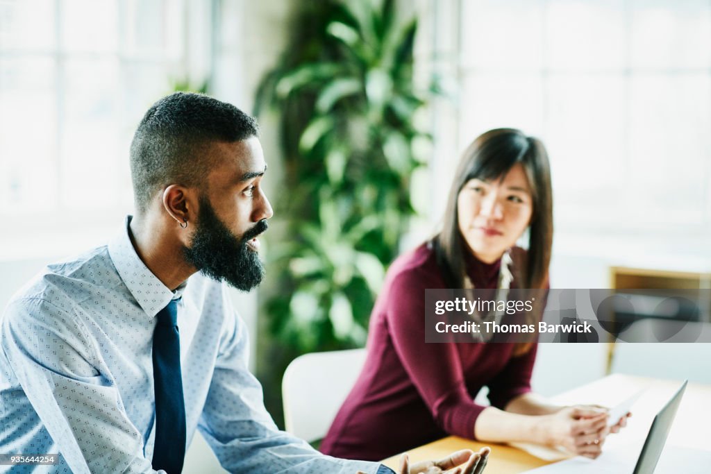 Business colleagues in discussion during client presentation in office conference room