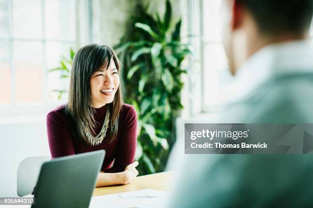 smiling businesswoman leading project meeting in office conference room - enfoque diferencial fotografías e imágenes de stock