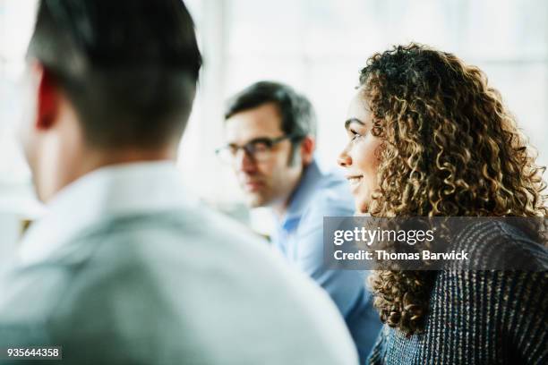 smiling businesswoman in discussion with colleagues during team meeting - true events stockfoto's en -beelden