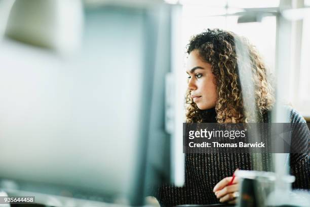 businesswoman reviewing project on computer monitor at workstation in office - challenge authority stock pictures, royalty-free photos & images