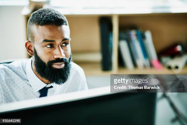 smiling businessman working on computer at office workstation - selective focus foto e immagini stock
