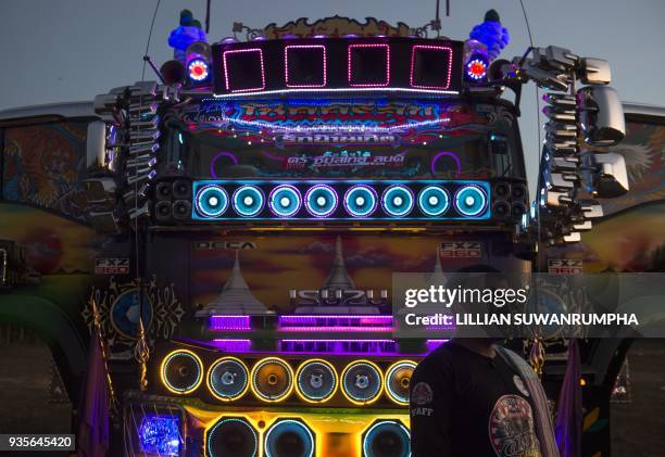 This photograph taken on December 23, 2017 shows a driver standing in front of his truck, decorated with mirrors and loudspeakers, at a fancy truck...