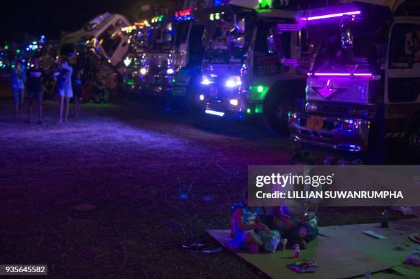 This photograph taken on December 23, 2017 shows families gathered in front of rows of custom-painted trucks at a fancy truck party in the Thai...