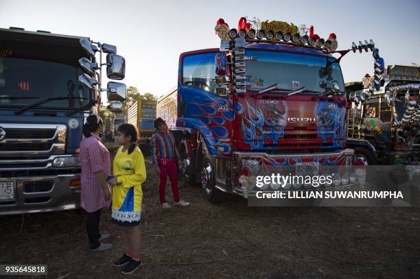 This photograph taken on December 23, 2017 shows a man standing next to his custom-painted truck at a fancy truck party in the Thai coastal province...