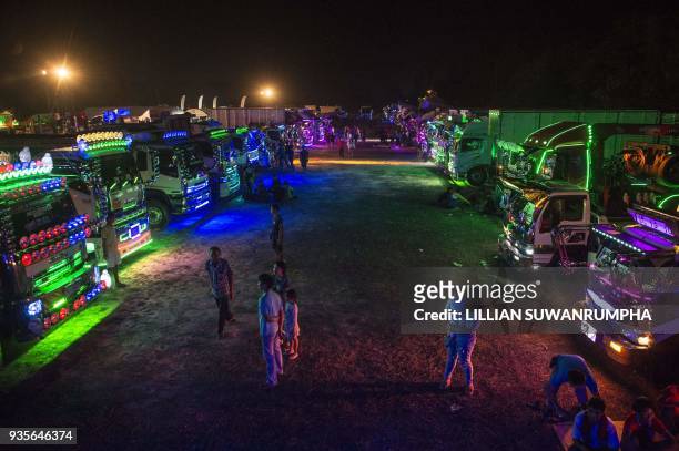 This photograph taken on December 23, 2017 shows rows of custom-decorated trucks parked in a field at a fancy truck party in the Thai coastal...