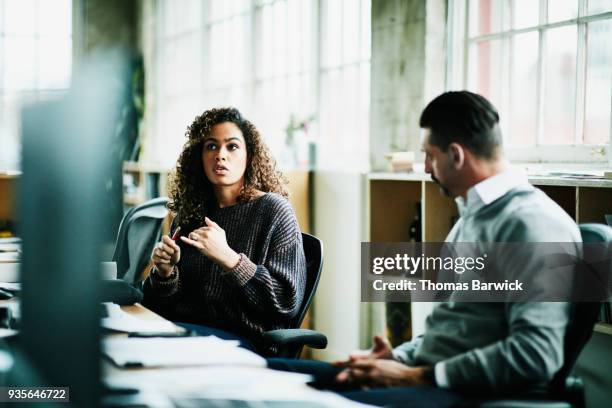 business colleagues discussing project at workstation in design studio - consultation at office desk imagens e fotografias de stock