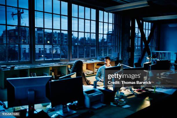 business partners sitting at workstation in design office working late - working overtime imagens e fotografias de stock