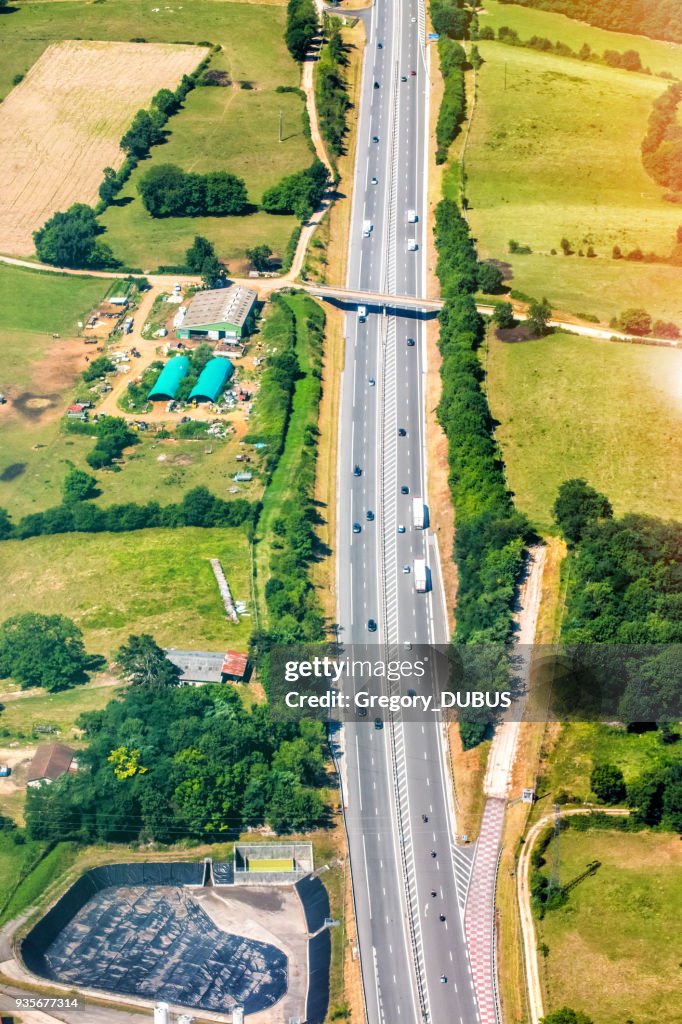 Aerial view of French highway road crossing lush foliage countryside in summer season