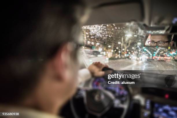 man rijdende auto bij nacht in de stad - rear view hand window stockfoto's en -beelden