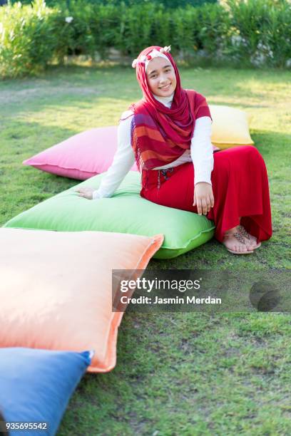 muslim girl sitting on big pillows on grass - hot big women stockfoto's en -beelden